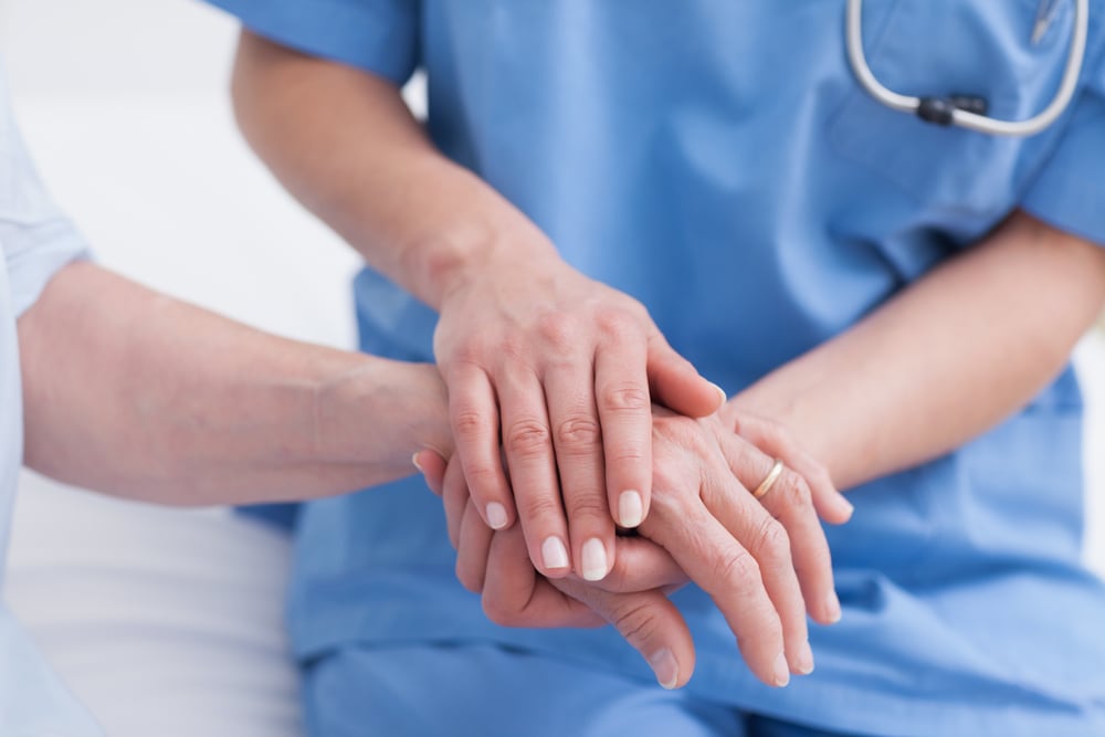Close up of a nurse touching hand of a patient in hospital ward Close up of a nurse touching hand of a patient in hospital ward